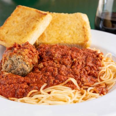 Spaghetti with a meatball in tomato sauce, served with garlic bread.