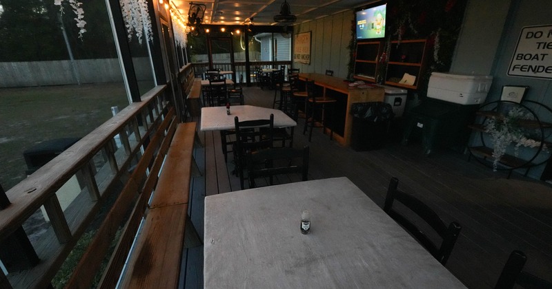 Covered outdoor seating area with wooden tables, string lights and floral decor.