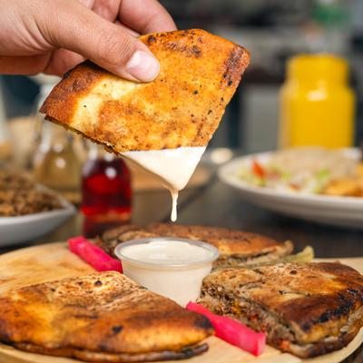 Hand dipping flatbread into creamy sauce.