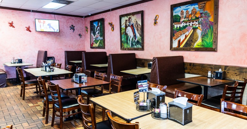 Interior of a restaurant with  wooden tables, and brown leather booths, decorated with murals and small sculptures.