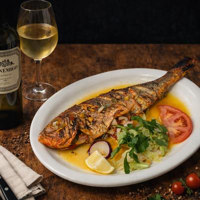 Whole grilled red snapper paired with fresh vegetables and white wine.
