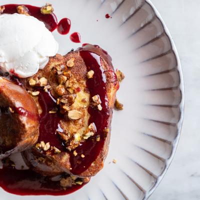 Challah bread in French Toast with caramelized pistachio, whipped cream and blackberry orange  sauce