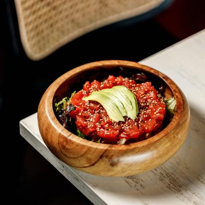 Fresh tuna tartare topped with sliced avocado and sesame in a bowl.