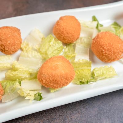 Chicken cordon bleu balls served with chopped lettuce on a white plate.