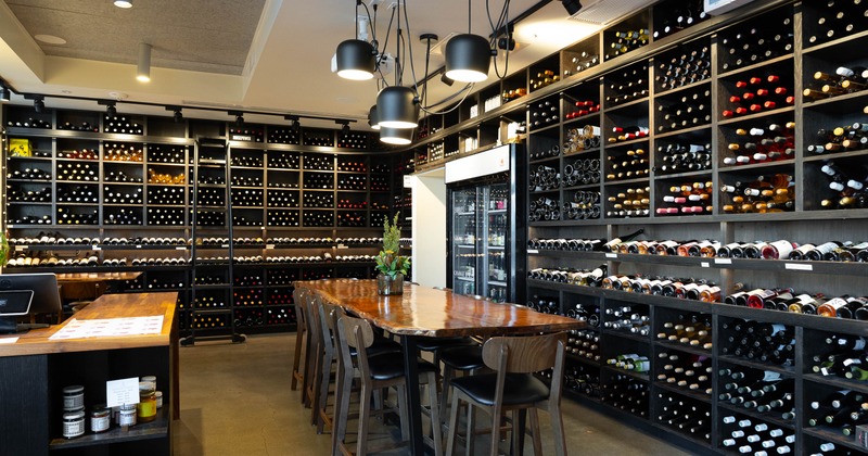 A wine bar - extensive wall-to-wall bottle displays, pendant lighting, wooden tables & chairs