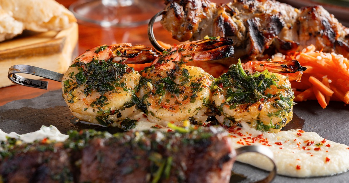 Grilled shrimp skewers with fresh herbs served over a creamy white puree