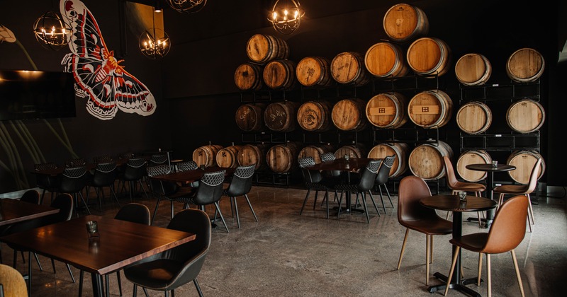 Seating area with tables and chairs, a wall decorated with mural art, and barrel racks