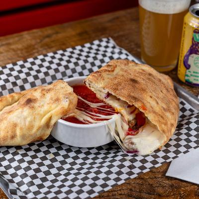 Supreme Calzone with a side of marinara and beer.