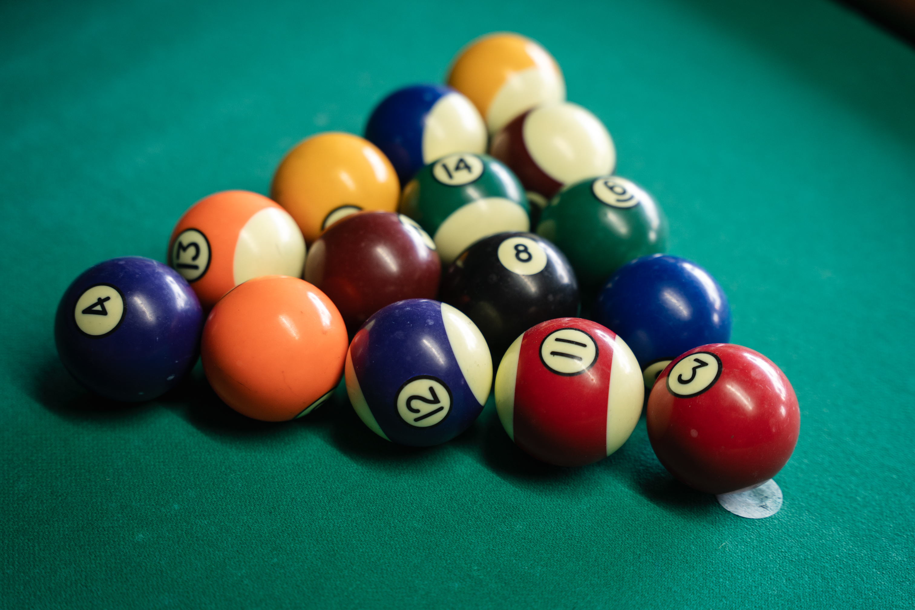 A set of billiard balls racked on a pool table felt