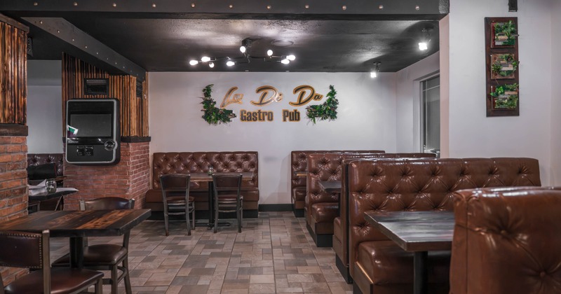 Interior of gastro pub, tufted leather booths, wooden tables and decorative green accents