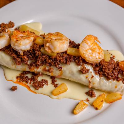 Chicken burrito, covered with cheese dip, chorizo, shrimps, and shredded pineapple.