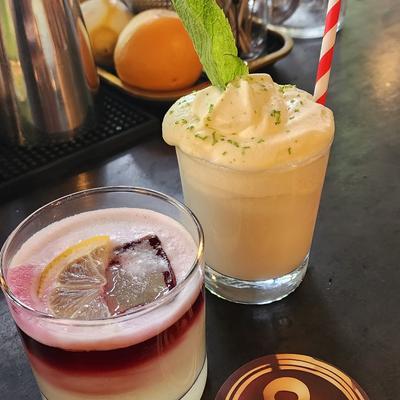 Two vibrant cocktails on a bar.