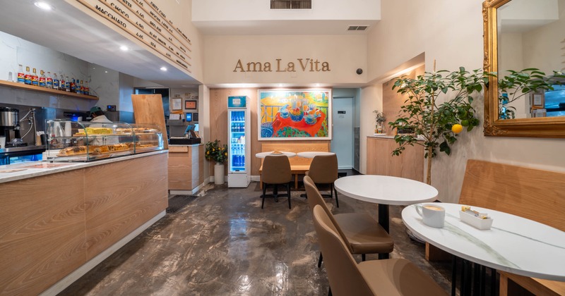 Interior of a cafe with wooden decor, seating area, pastry display, and a vibrant painting