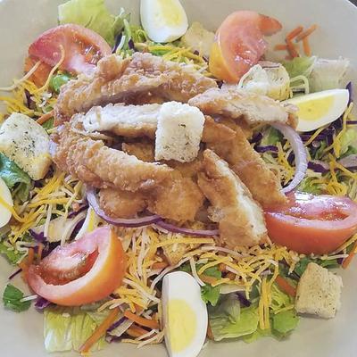 Salad with breaded chicken, hard-boiled eggs, grated cheese and fresh vegetables.