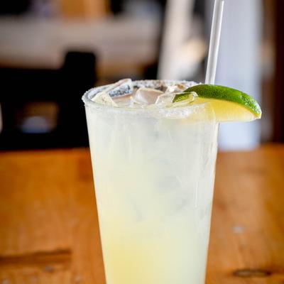 Margarita cocktail in a tall glass on a wooden table.