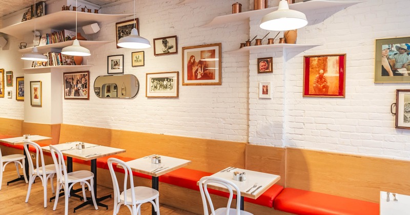 Interior, banquette seating and tables by a wall, pictures on the wall