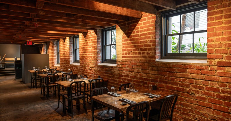 Rustic restaurant dining room with exposed brick walls, wooden tables, black chairs