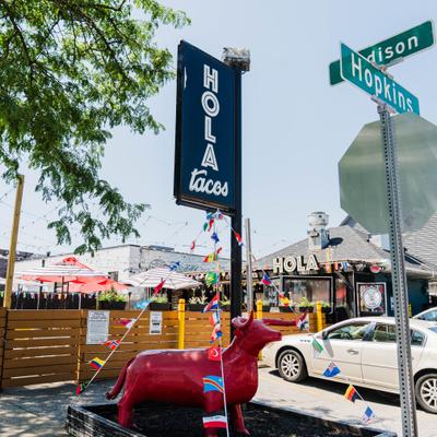 Exterior featuring fenced patio, signage and a red bull statue.