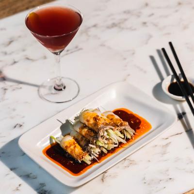 Garlic Pork Belly plate and a drink served on a white marble table.