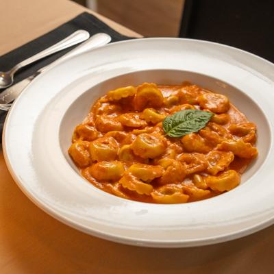 Tortellini covered in a creamy tomato sauce and garnished with basil.