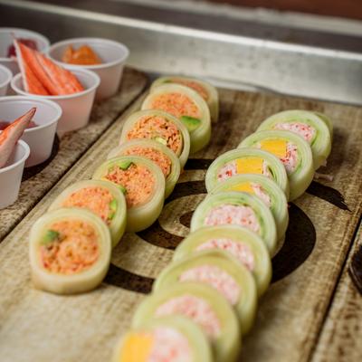 Cucumber-wrapped sushi rolls filled with crab and spicy tuna on a tray.
