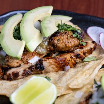 Grilled chicken tacos toped with avocado slices.