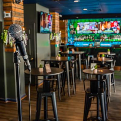 A microphone stand on a stage with seating area and bar in the background.