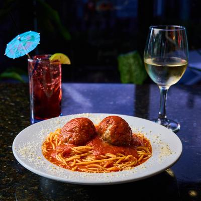 Spaghetti with meatballs, accompanied with white wine and vodka cranberry drink.
