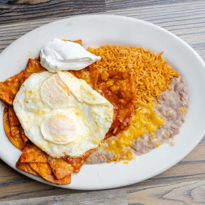 Chilaquiles topped with fried eggs, served with rice, refried beans and sour creme.