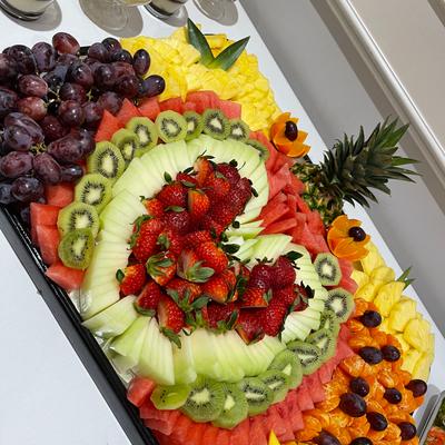 Fruit platter featuring a heart-shaped centerpiece filled with sliced strawberries.