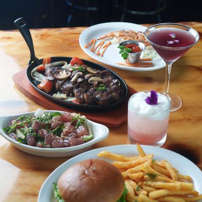 Various dishes served on the table alongside cocktails.