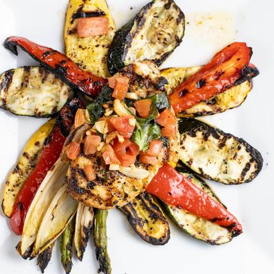 Grilled chicken topped with diced tomatoes and herbs, served with charred vegetables.