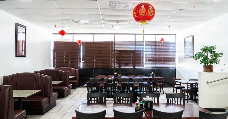 Interior with a mix of booth and table seating, potted plants and red lanterns