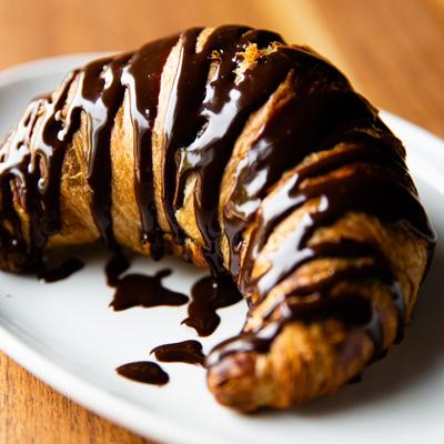 A croissant drizzled in chocolate sauce.