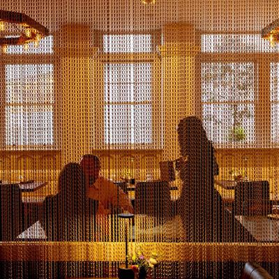 A view of patrons sitting at tables behind the mesh curtains in dining space.