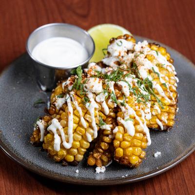 Mexican street corn served with dipping sauce and a lemon.