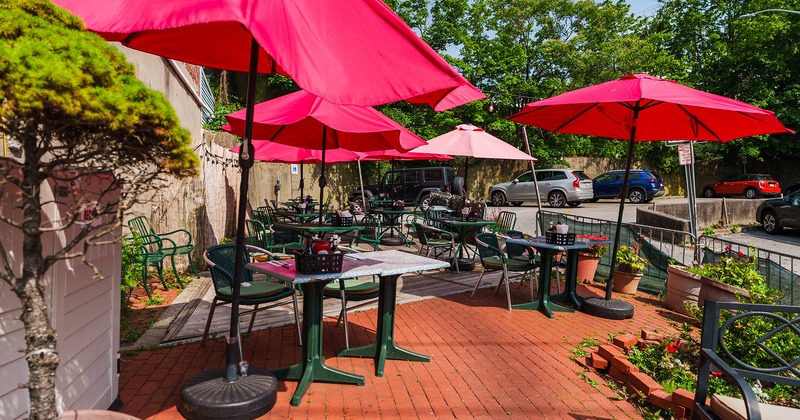 Outdoor seating area with tables, chairs, and red parasols