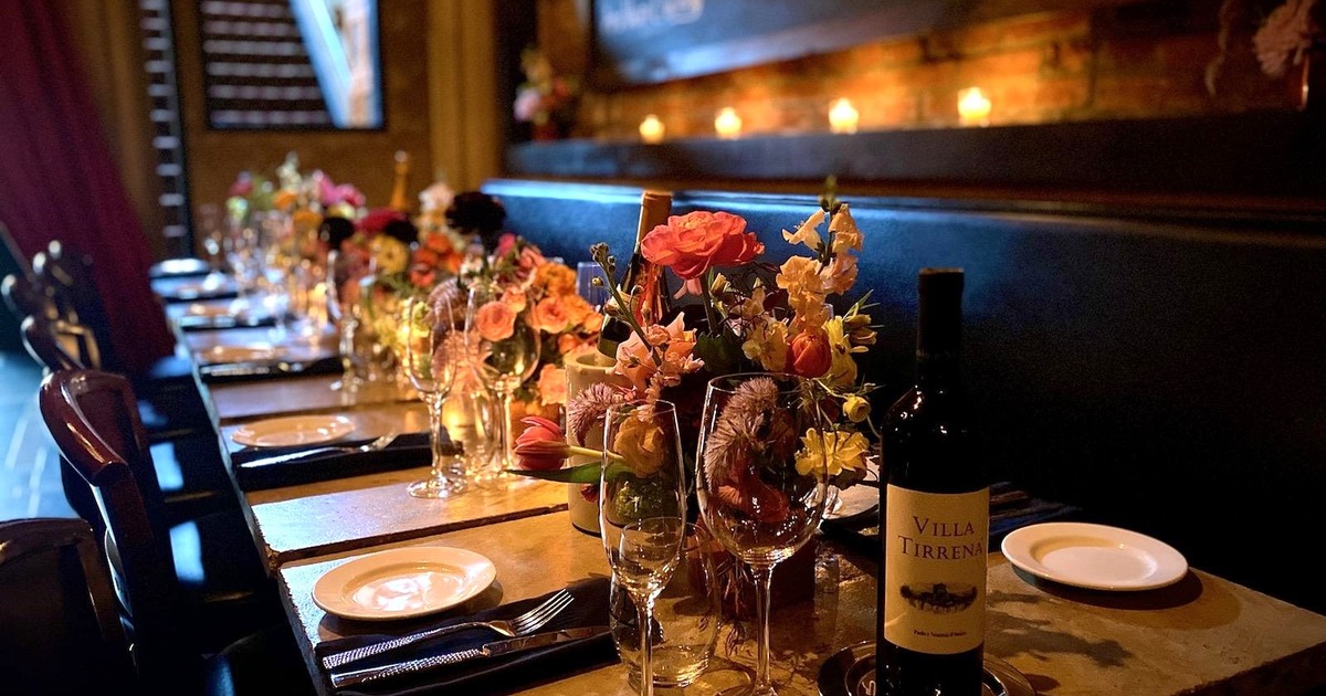 Tables with plates, napkins, utensils, wine, glasses, and floral centerpieces