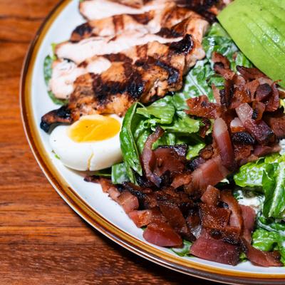 Chicken Cobb Salad, with bacon, lettuce, tomatoes, egg, cheese, croutons, and dressing.