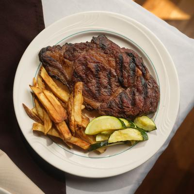 Grilled Ribeye with a side of fries and vegetables, overhead view.