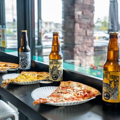 Assorted pizza slices and beer bottles on a window counter.