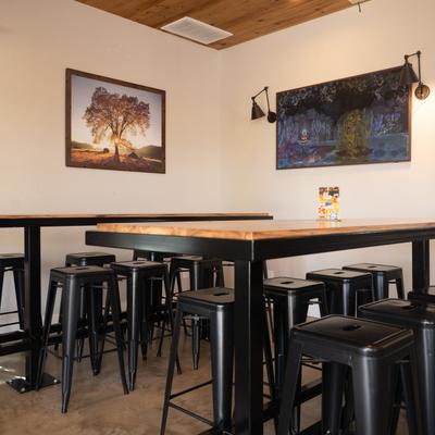 Interior, wooden tables and black metal stools, walls adorned with artwork.