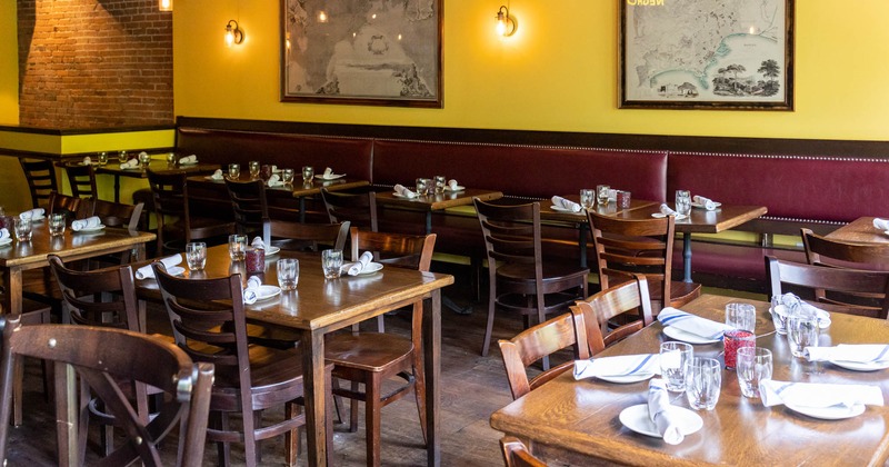 Interior, long banquette seating and dining tables ready for guests, pictures on the wall