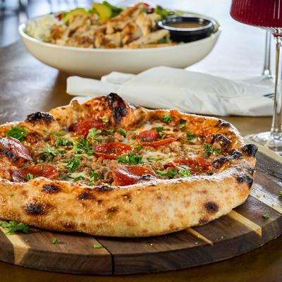 Meat Lovers pizza served on wooden board.