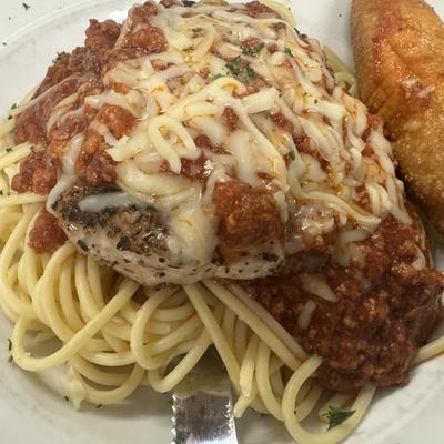 Chicken Parmesan served over spaghetti with marinara sauce.