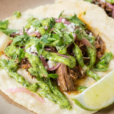 Smoked brisket taco with avocado, greens, and lime.