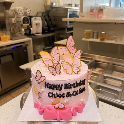 Pink frosted birthday cake decorated with golden pink butterflies and pearls.