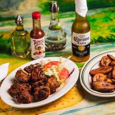 Bone-in chicken served with salad, fried plantains, bottle of beer and condiments.