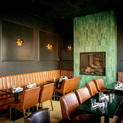 Interior, a room with tables and banquette seating in front of a cozy fireplace.