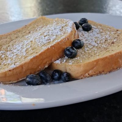 Thick Italian white bread dredged in an egg, cinnamon and cream, powdered sugar, and blueberries.